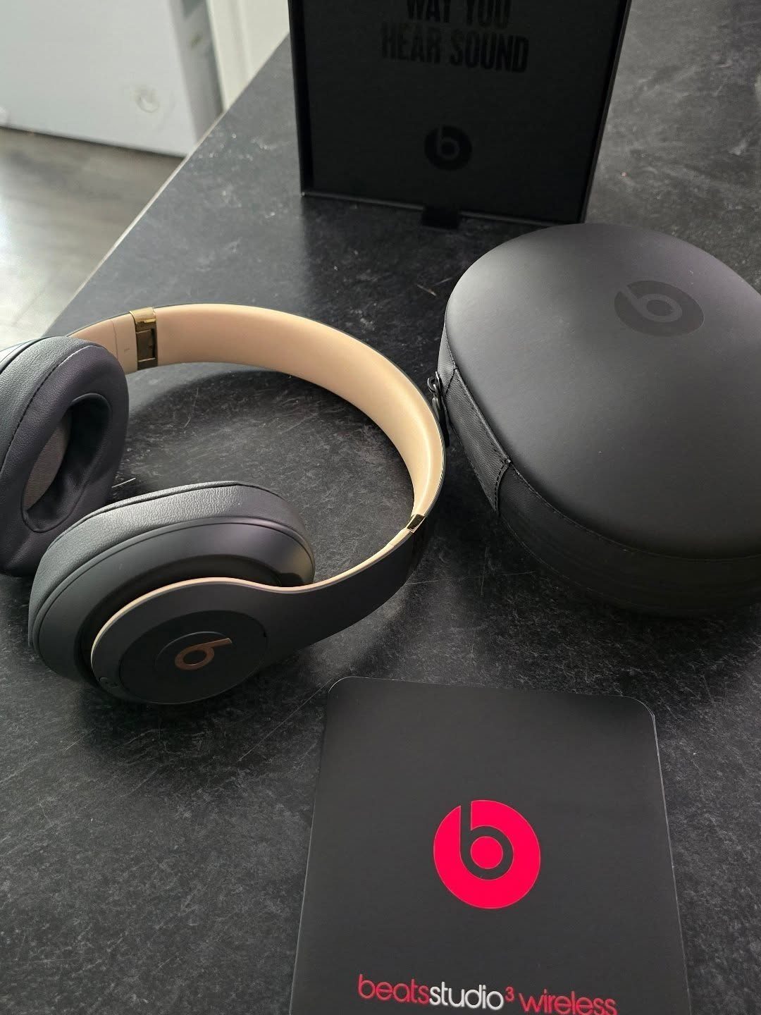 Black and tan over-ear headphones with a carrying case on a dark surface.