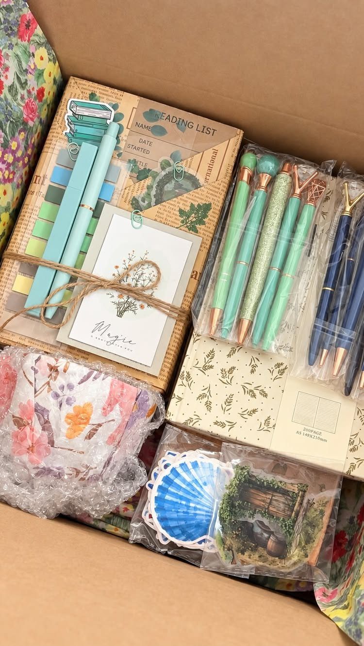 Artisan gift box containing a notebook, colorful pens, and floral stationery accessories.