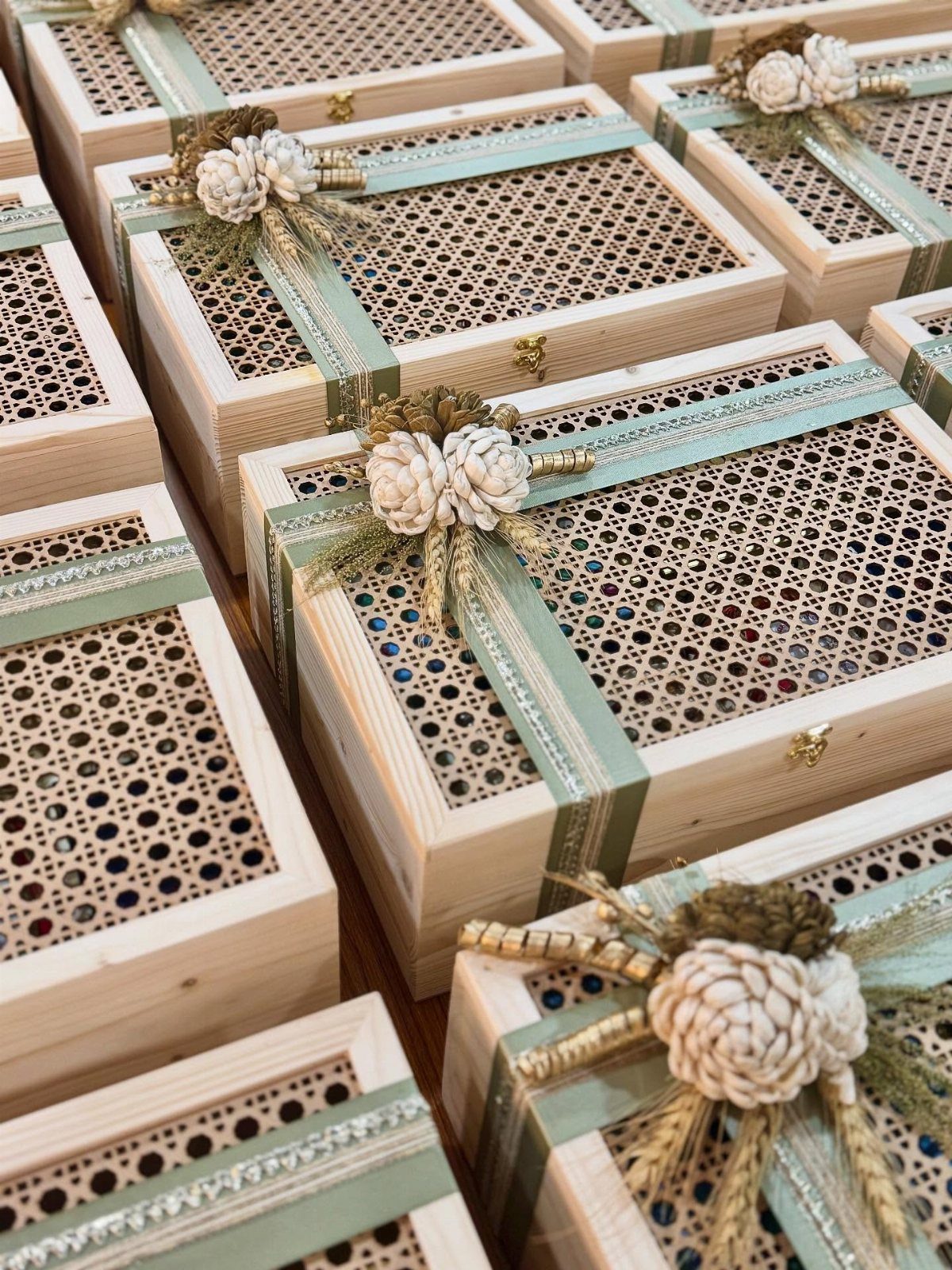 Wooden gift boxes with lattice lids, green ribbons, and floral pinecone decorations.