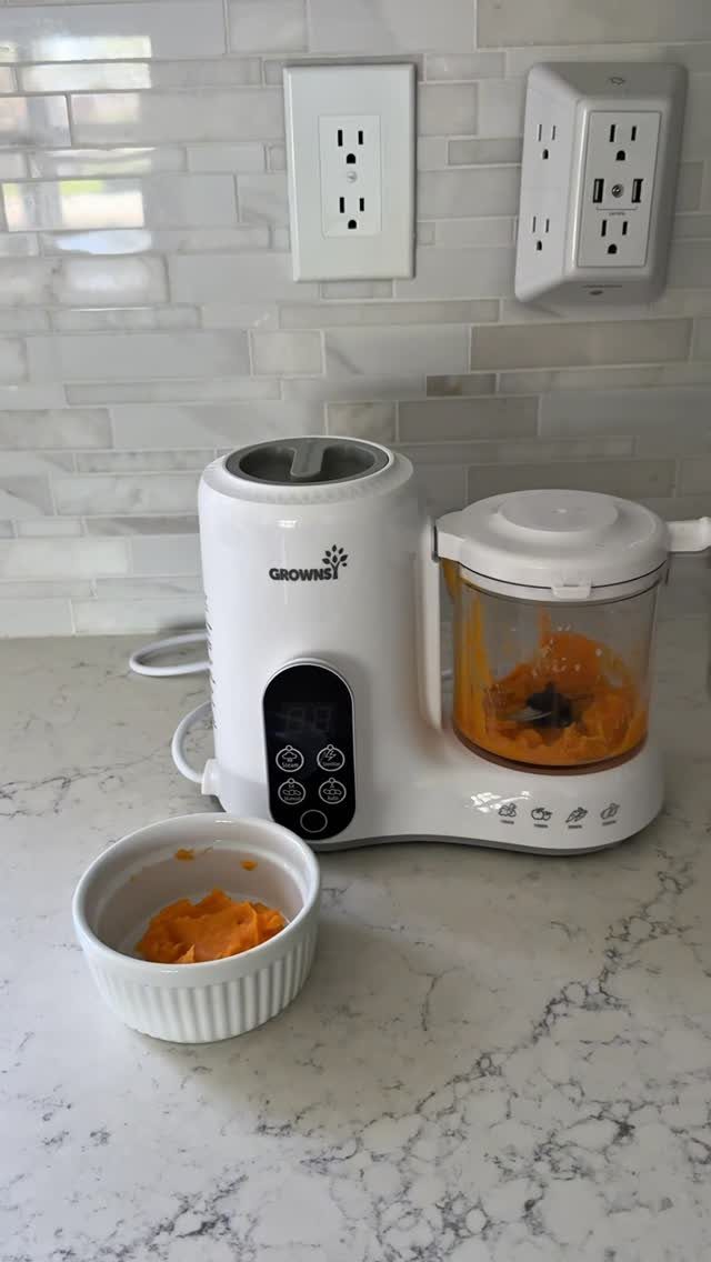 White baby food maker on marble counter with orange puree in a bowl.