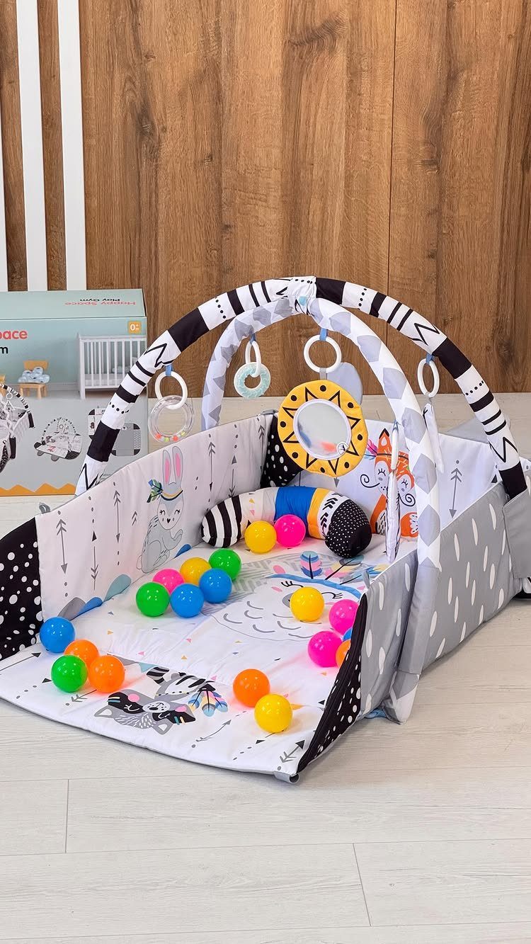 Baby play mat with padded walls, overhead arch, and colorful plastic balls.