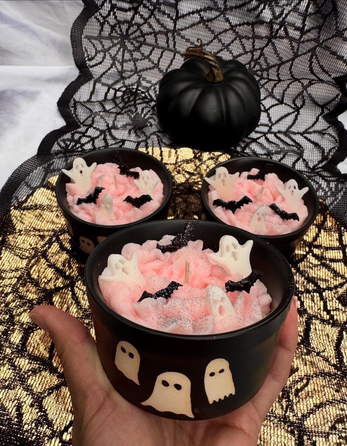 Halloween candles with pink whipped wax, ghosts, and bats in black jars.