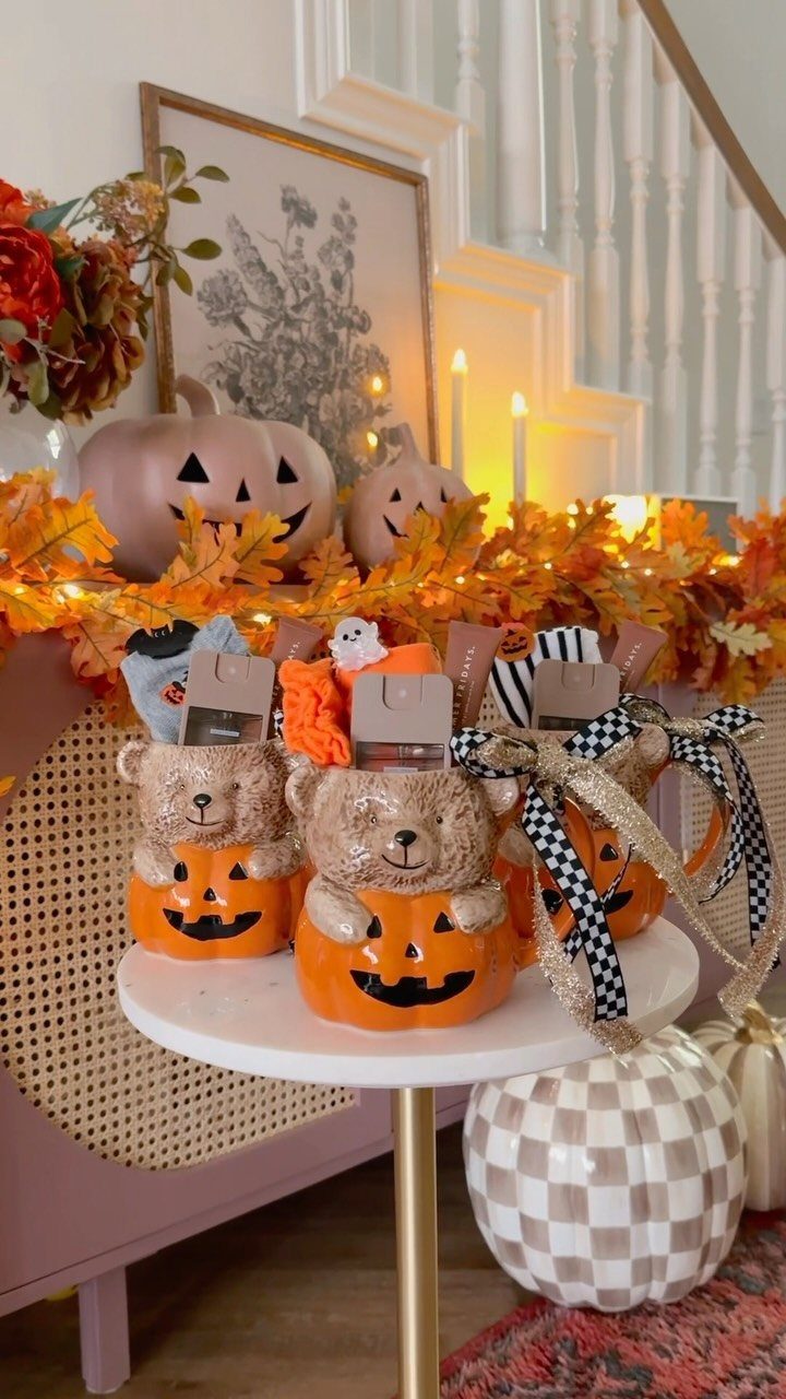 Bear-shaped pumpkin mugs filled with rolled socks and ribbons on a white table.