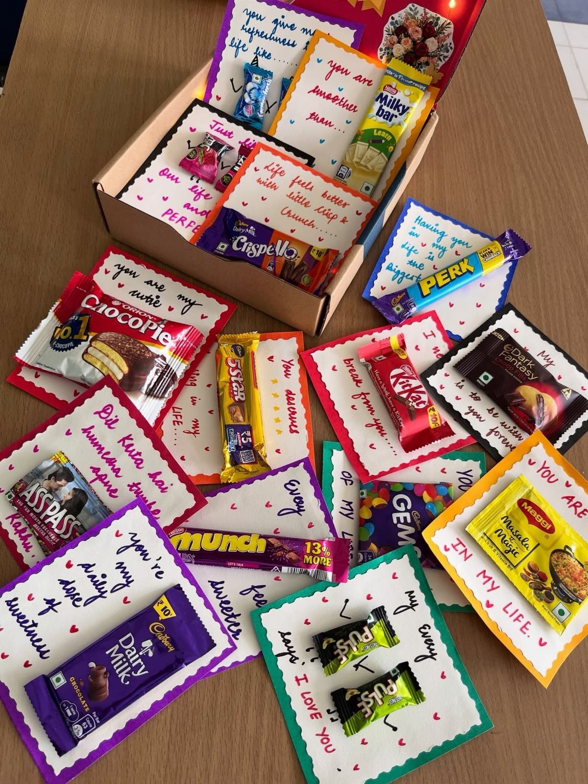 Handmade gift cards with various chocolate bars and handwritten notes in a box.