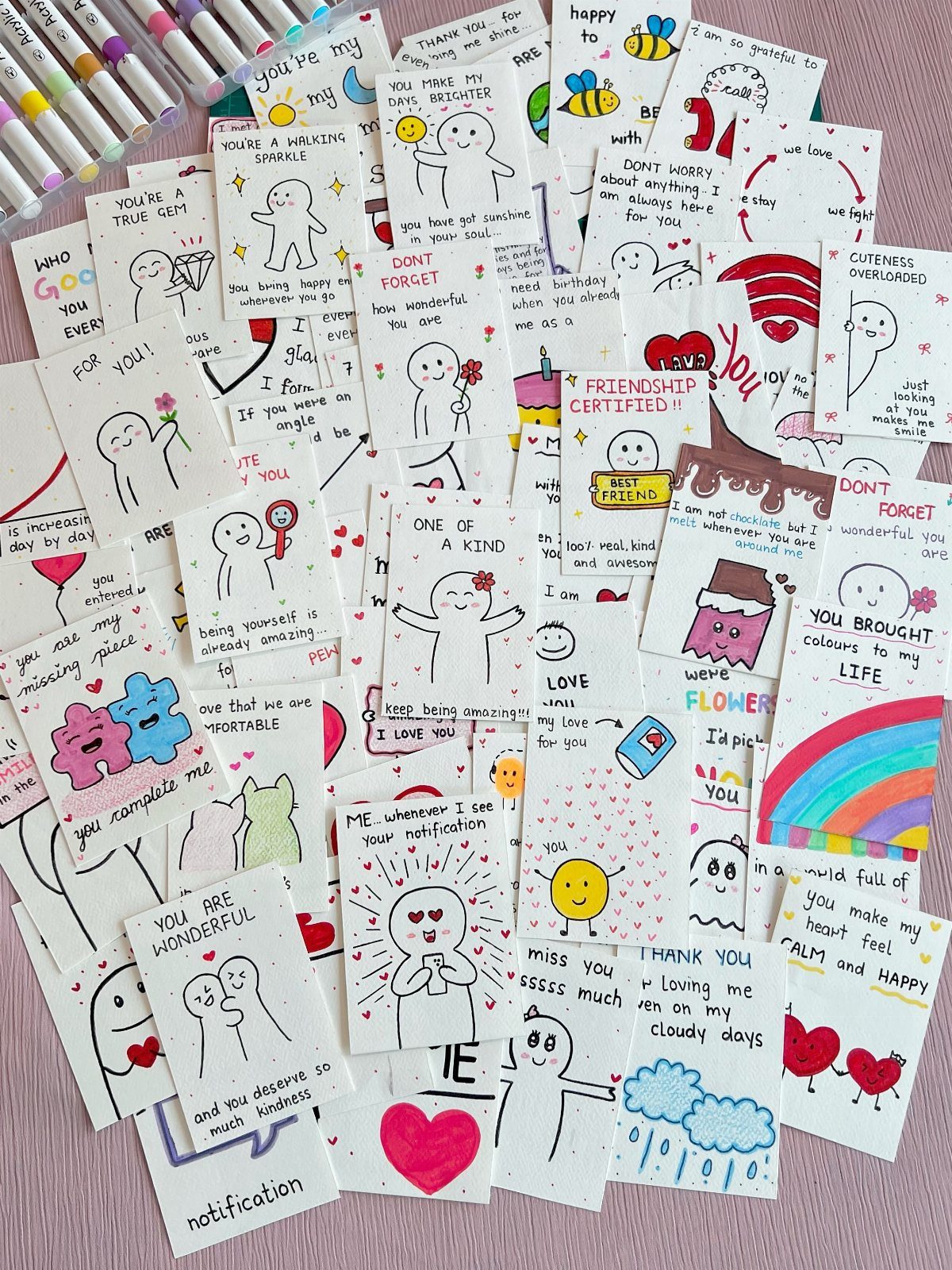 Handmade friendship cards with cute drawings and positive messages scattered on a surface