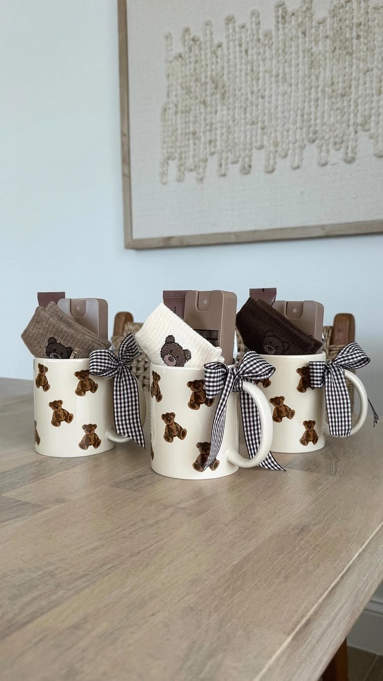 Three bear-patterned mugs filled with chocolate and gift bags tied with checkered bows.