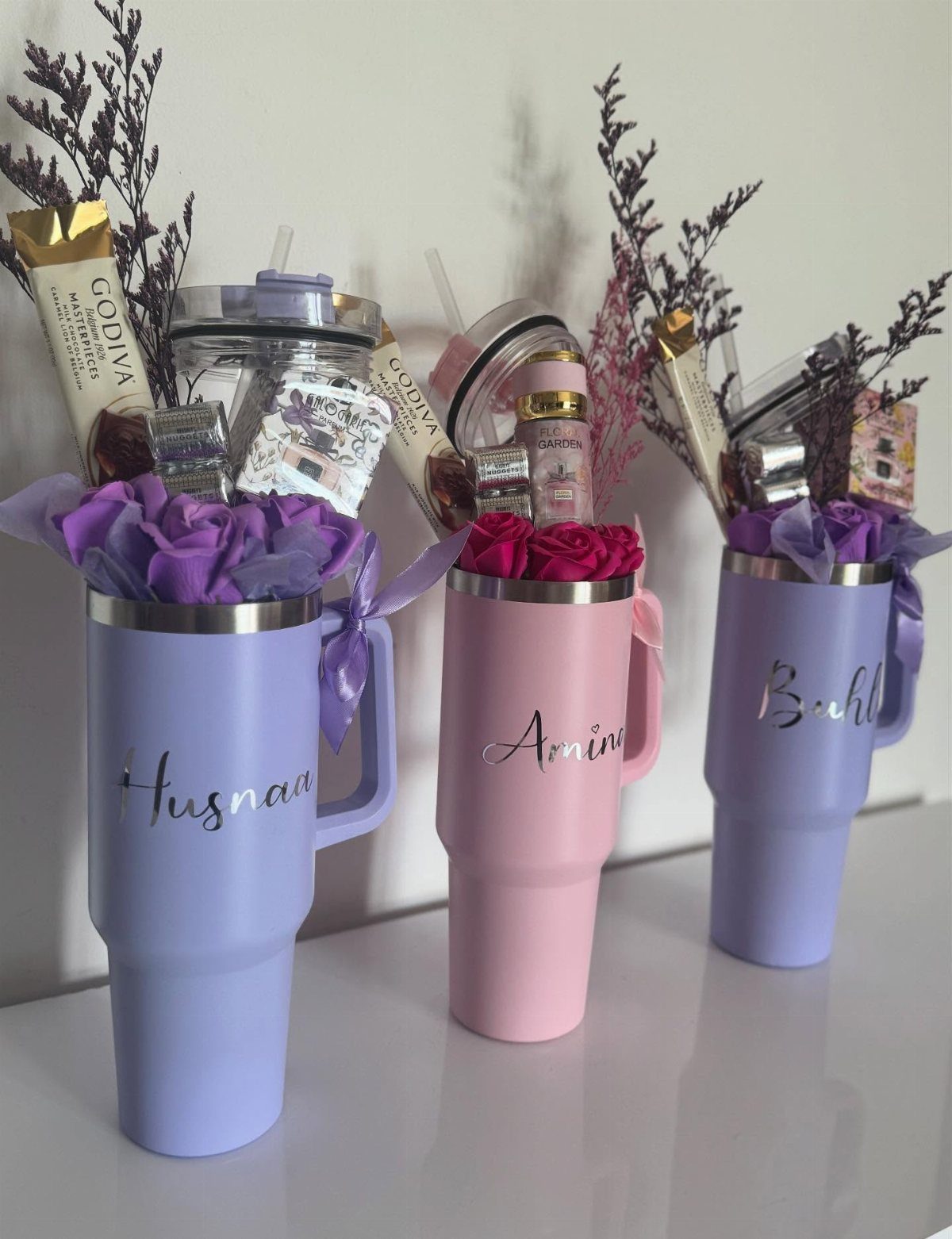 Personalized colorful tumblers filled with chocolates and flowers as gift baskets.