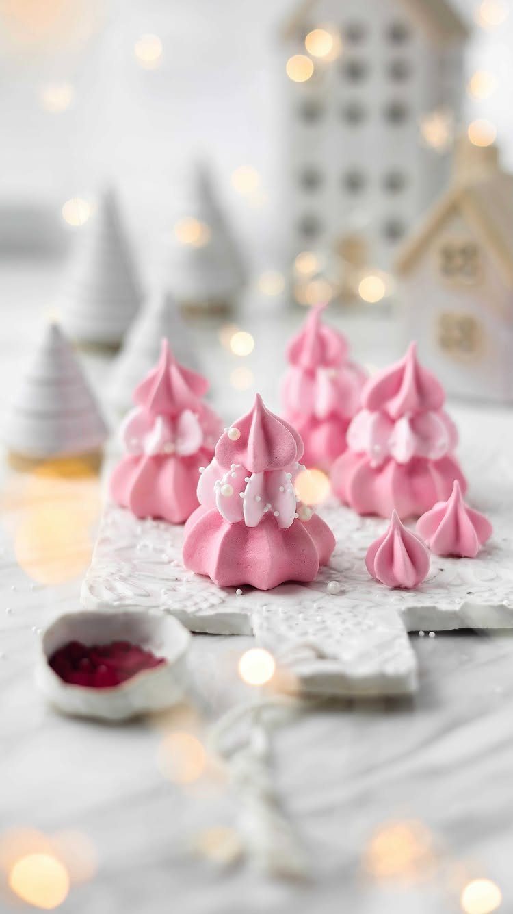 Pink tree-shaped meringue cookies with white pearls on a white festive background