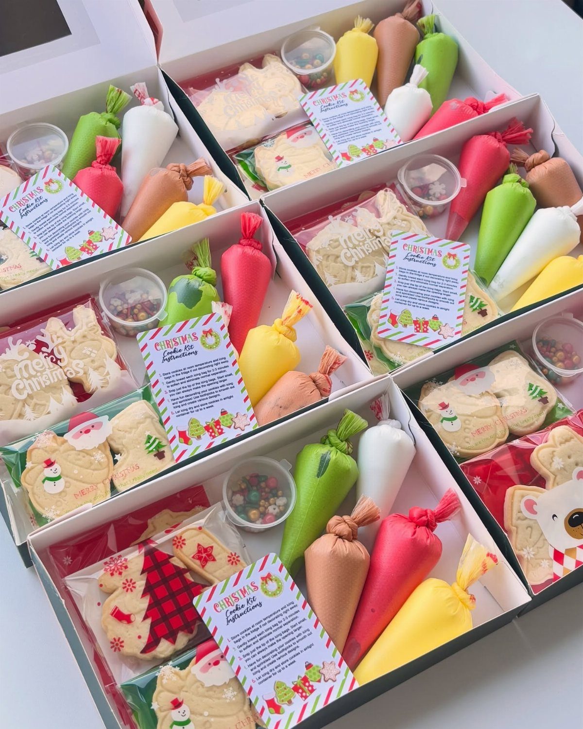 Cookie decorating kits in white boxes with frosting piping bags and sprinkles.