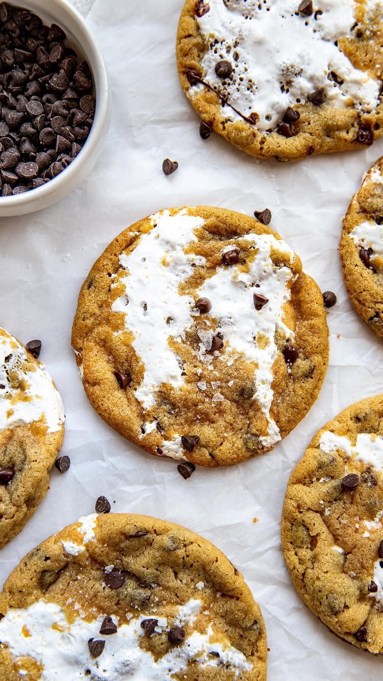 Golden-brown cookies topped with melted marshmallow and chocolate chips on white parchment paper.