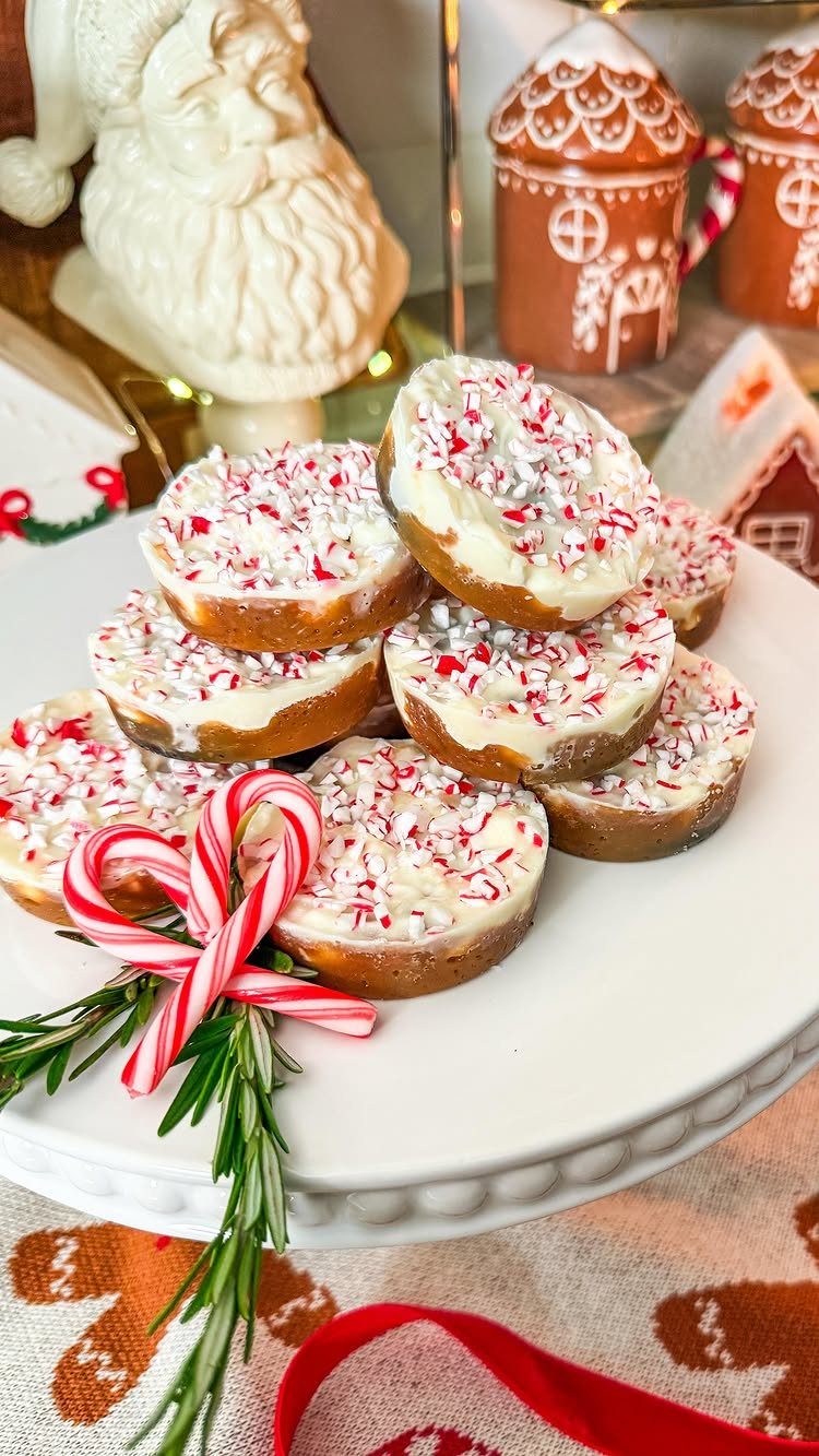 Peppermint bark cookies with white frosting and crushed candy on a white stand.