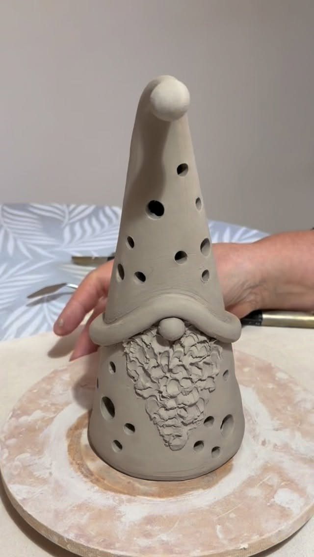 Clay gnome figure being crafted on a pottery wheel with a textured beard.