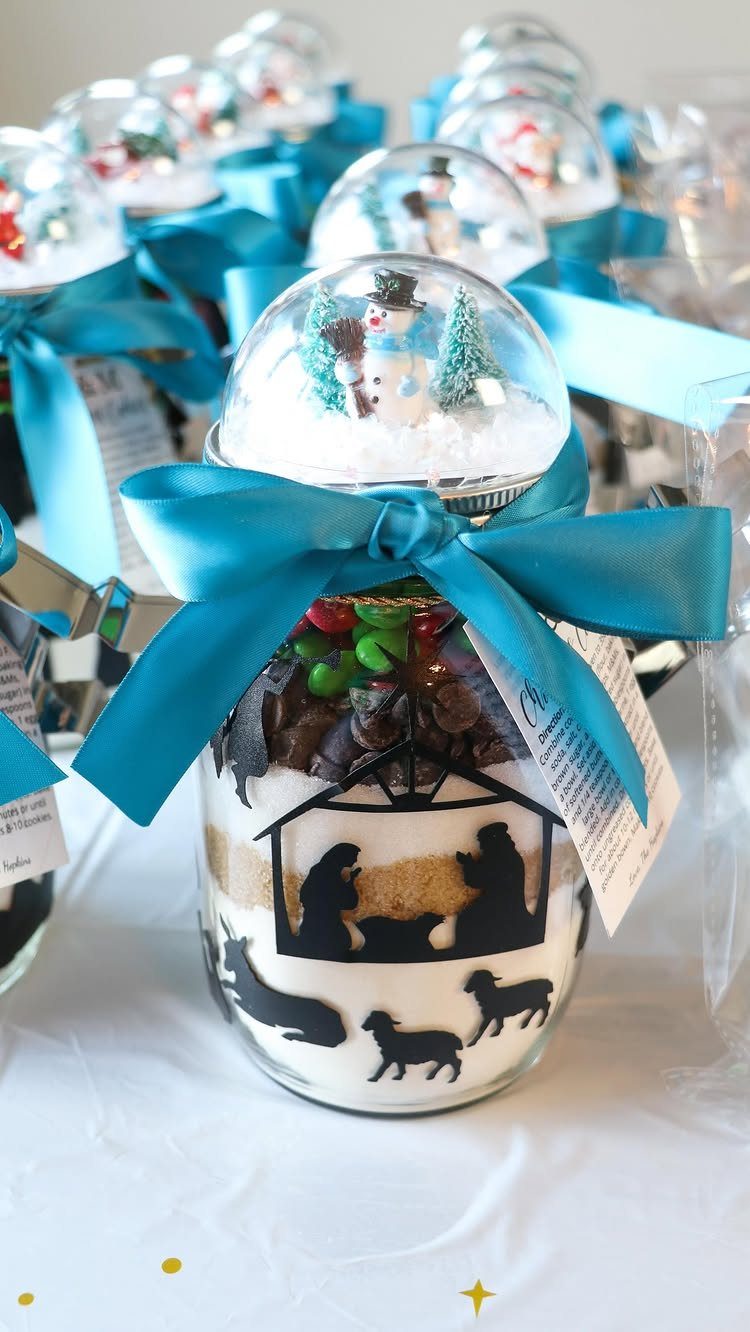 Glass jars with layered ingredients, blue ribbons, and snow globe lids for gifts.