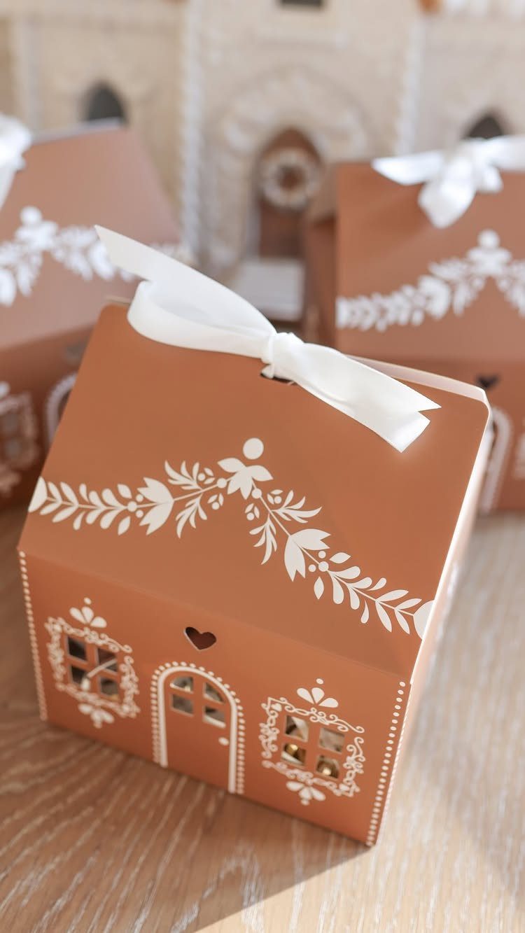 Brown house-shaped gift boxes with white floral patterns and white ribbon bows.