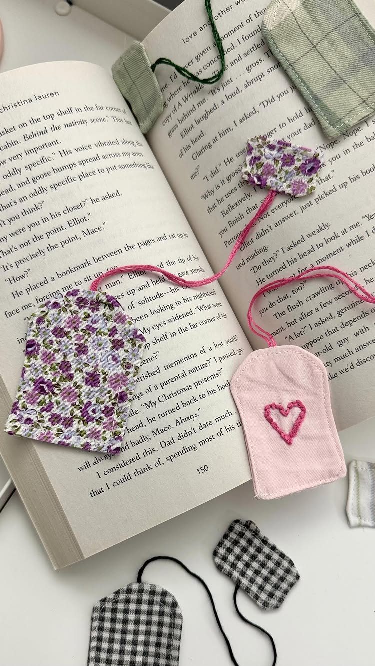 Handmade fabric bookmarks in various patterns resting on an open book.