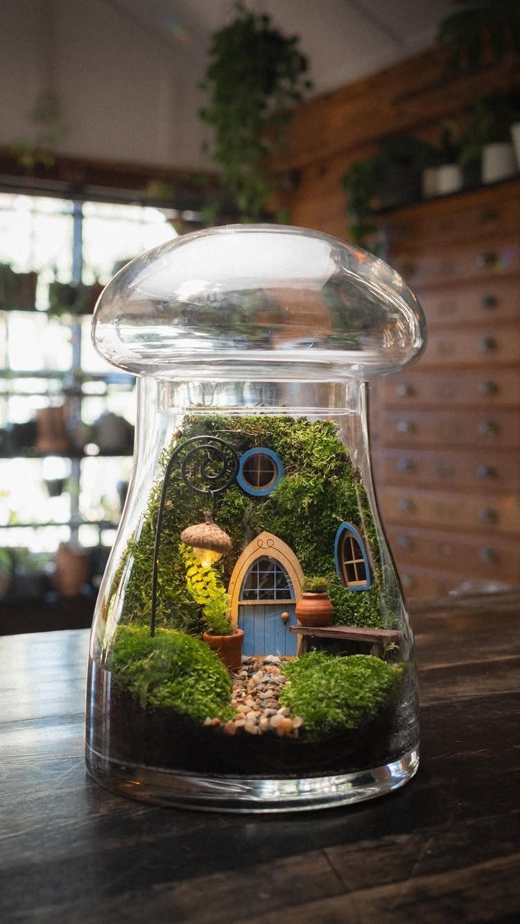 Miniature fairy house with blue door and moss inside a glass jar