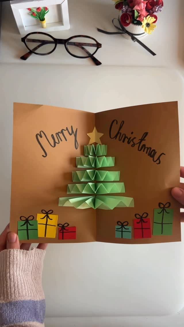 Handmade Christmas card with a 3D green paper tree and colorful paper gifts.