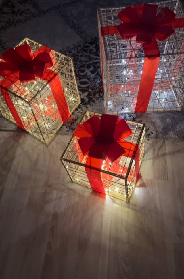 Wire mesh gift boxes with red ribbons and glowing fairy lights on floor