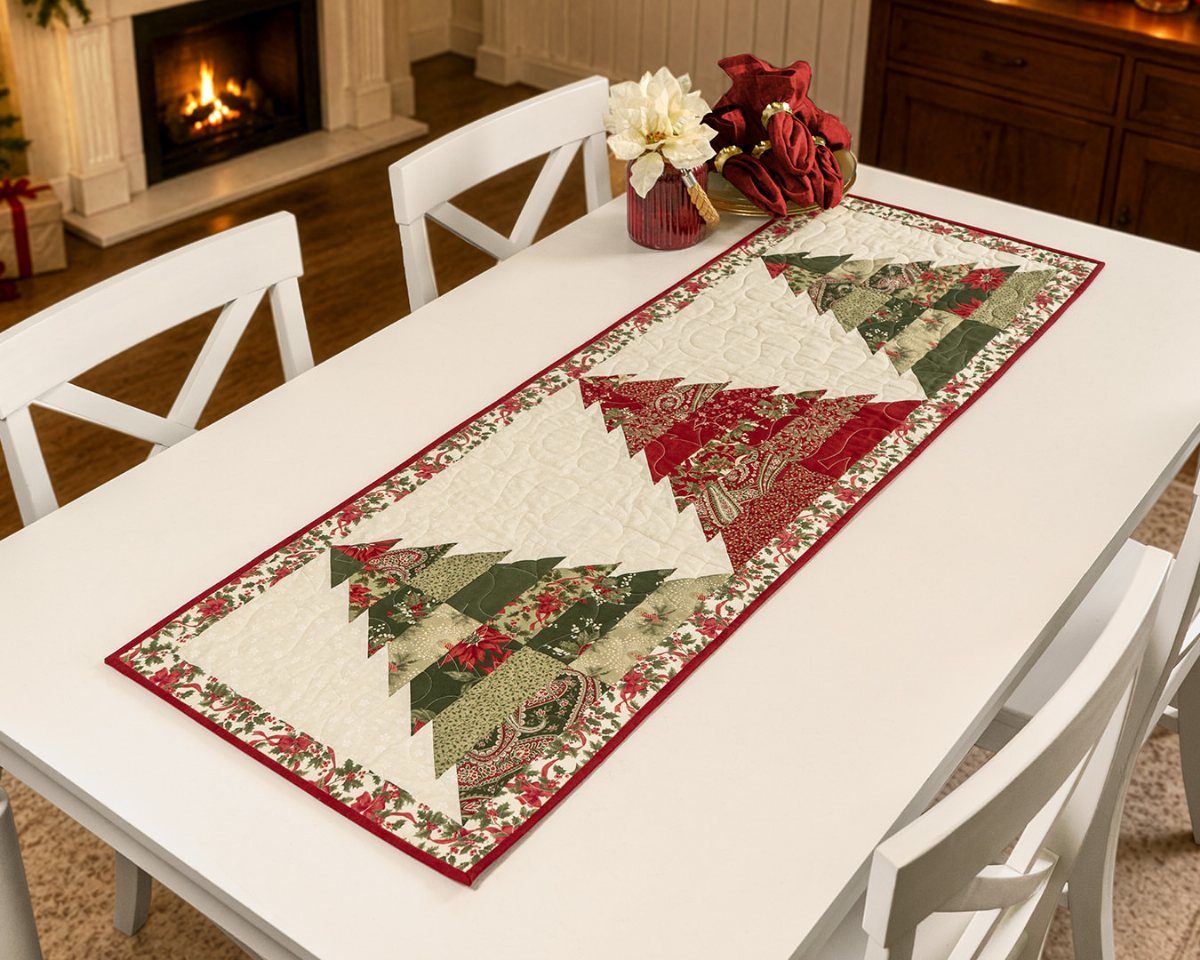 Quilted Christmas table runner with red and green tree patterns on white table
