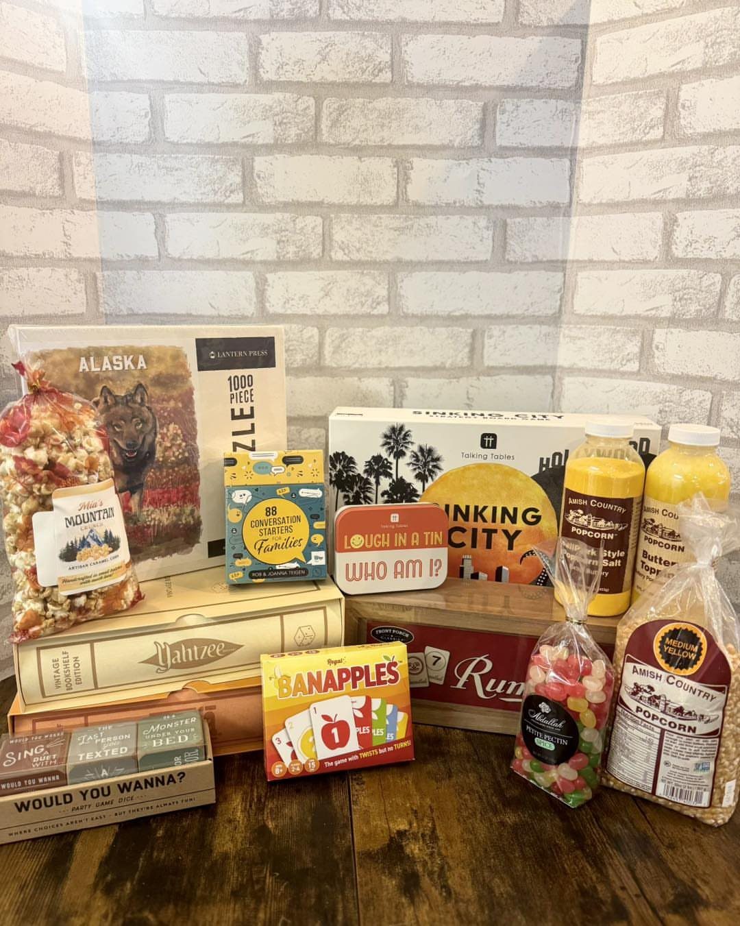 Board games, a puzzle, popcorn, and drinks arranged as a family game kit.