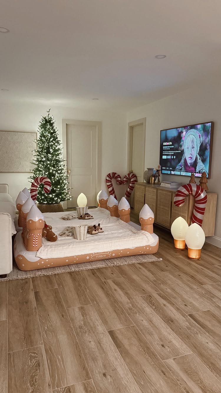 Gingerbread house inflatable lounge in a living room with a Christmas tree and TV.