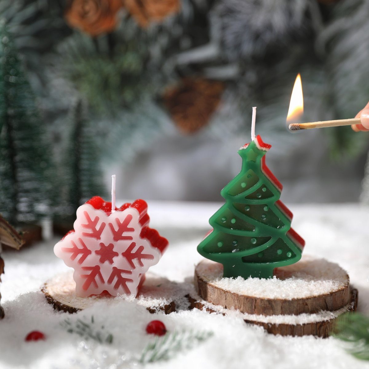 Christmas tree and snowflake candles on wooden slices in a snowy winter setting