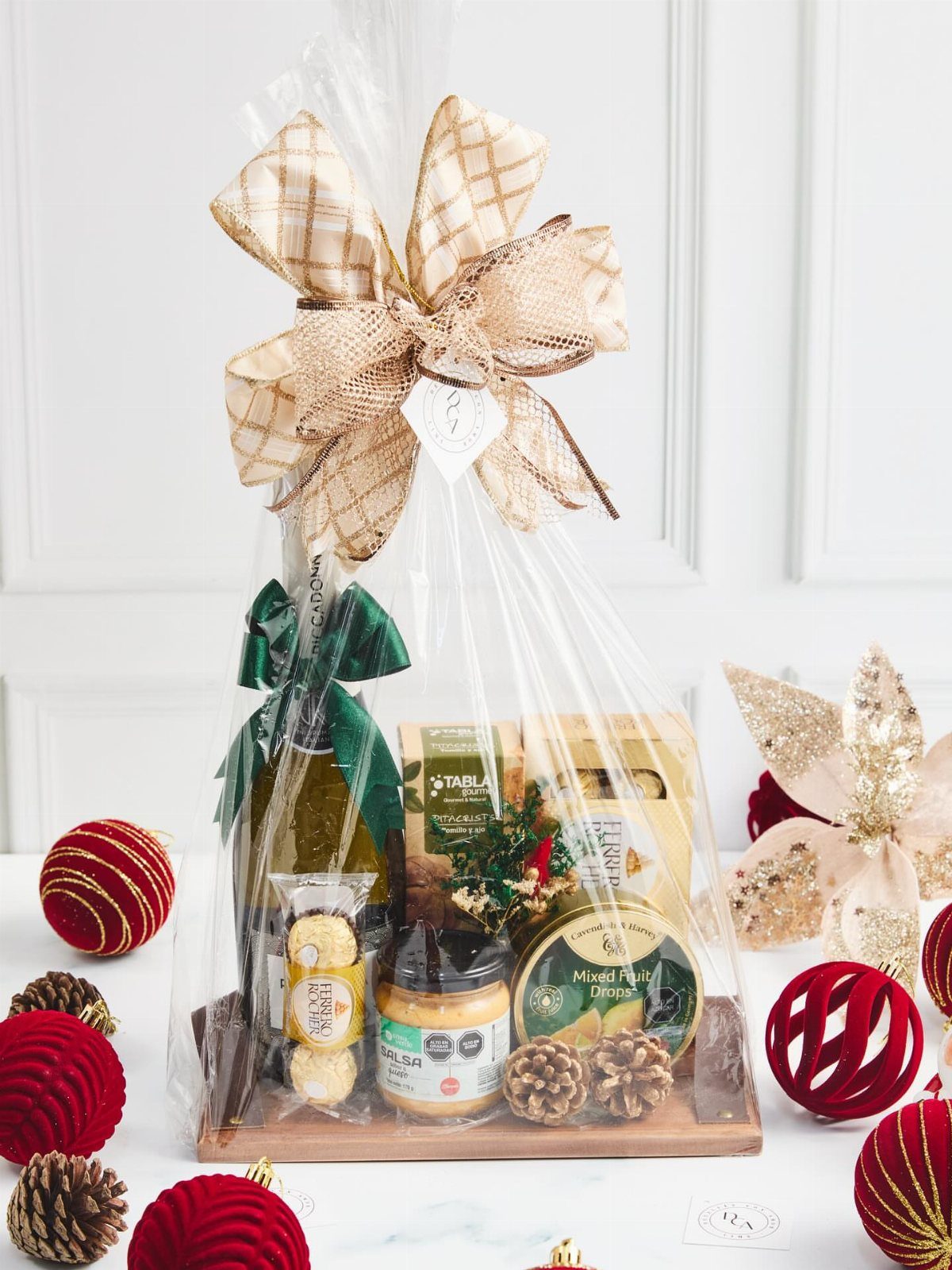 Gourmet food gift basket with wine and snacks wrapped in cellophane with a bow.