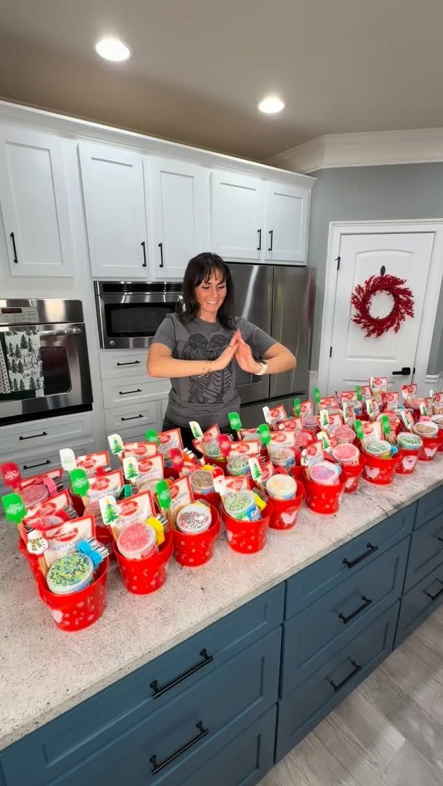 Woman standing behind a kitchen counter filled with red gift buckets for staff.