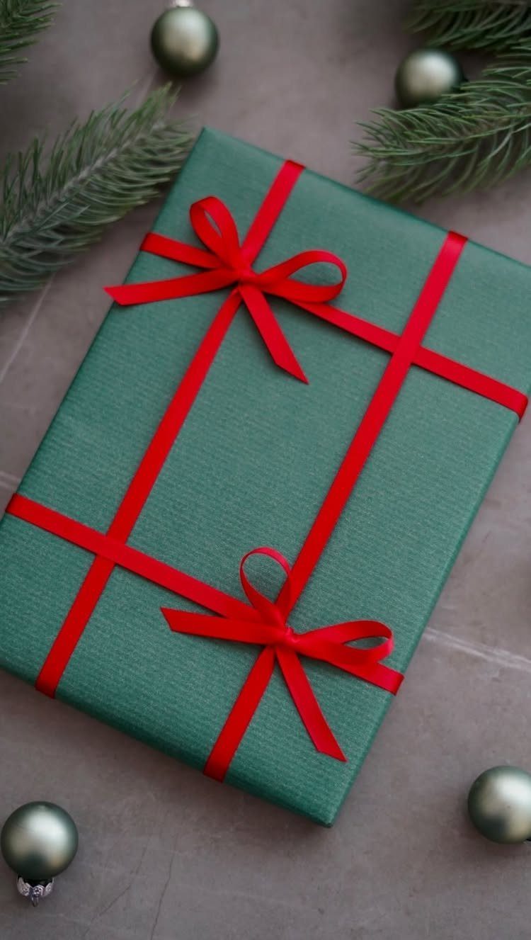 9 Christmas Gift Ribbon Ideas for Pretty Wrapped Presents 9 Green gift box wrapped with red ribbons and two simple bows.