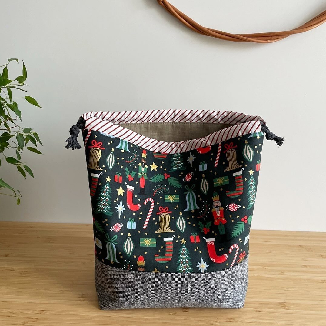Christmas themed fabric drawstring bag with grey base on a wooden table