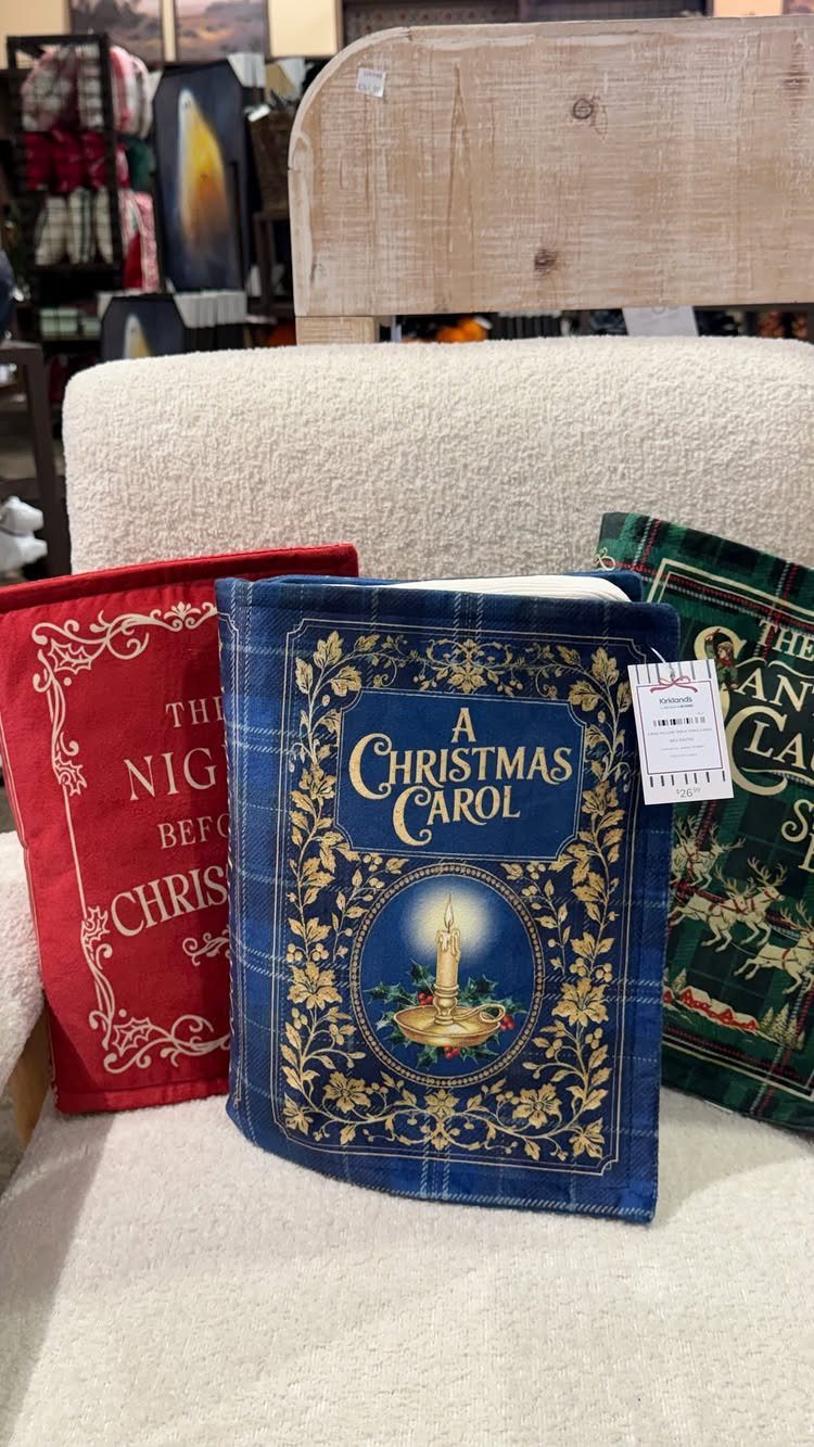 Three festive fabric Christmas stockings with holiday designs resting on a white chair.