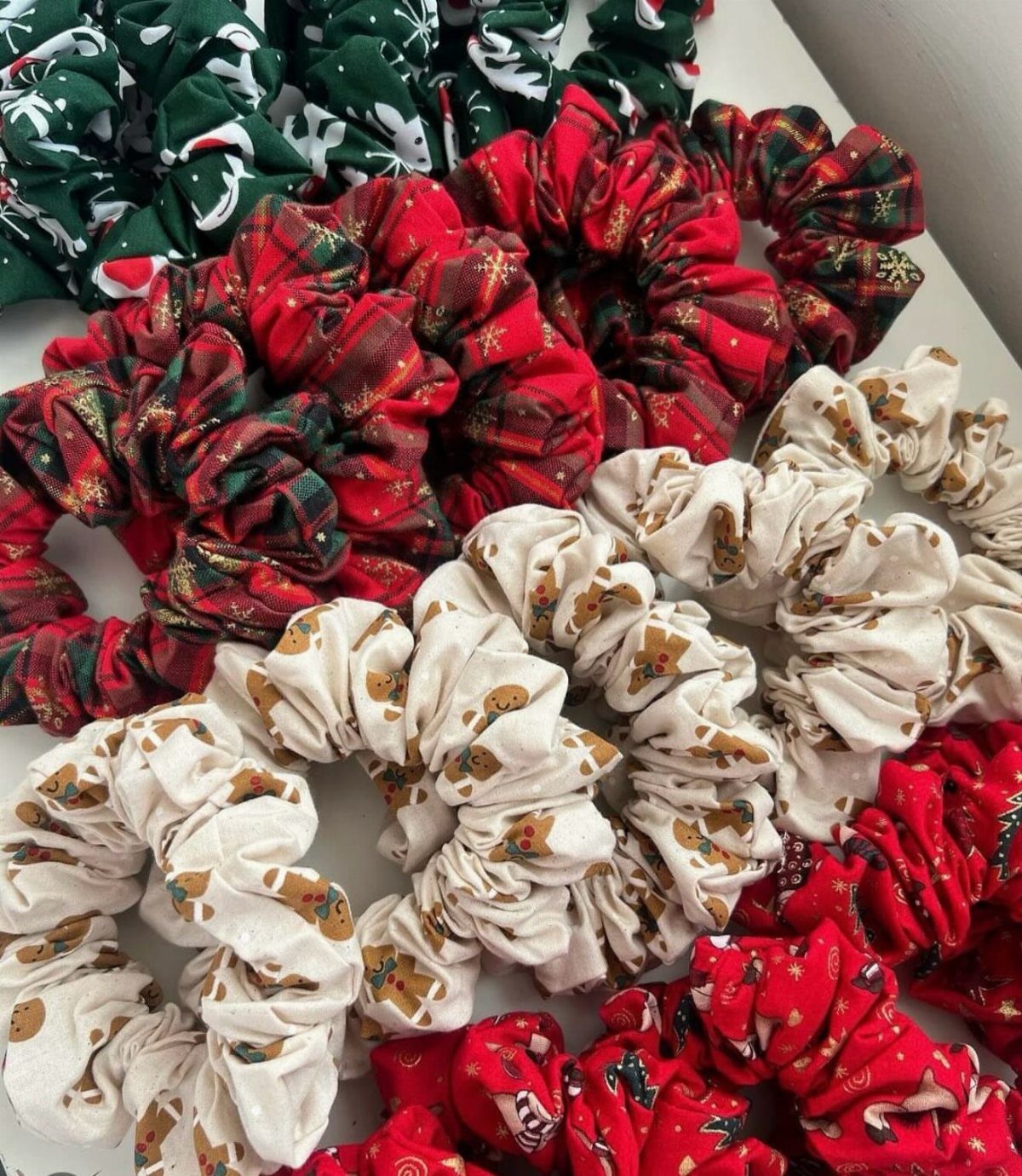Christmas themed fabric scrunchies in red, green, and white on a white surface