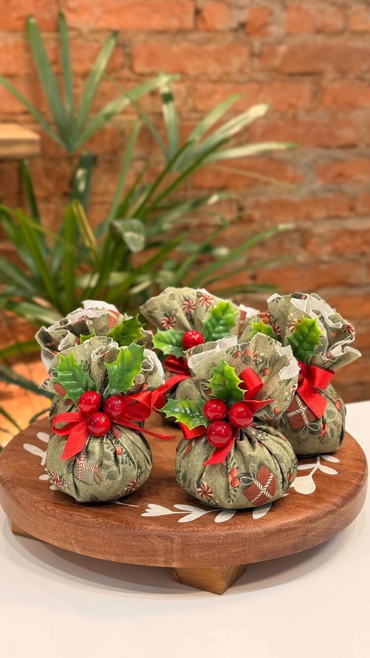 Small green plaid fabric sachets tied with red ribbons and festive berry decorations.