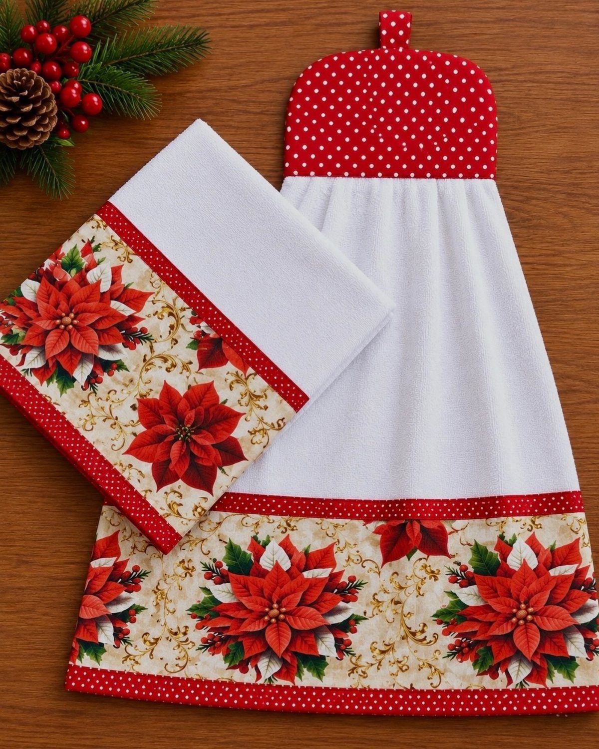 White kitchen towels with red poinsettia patterns and polka-dot trim on wooden background.