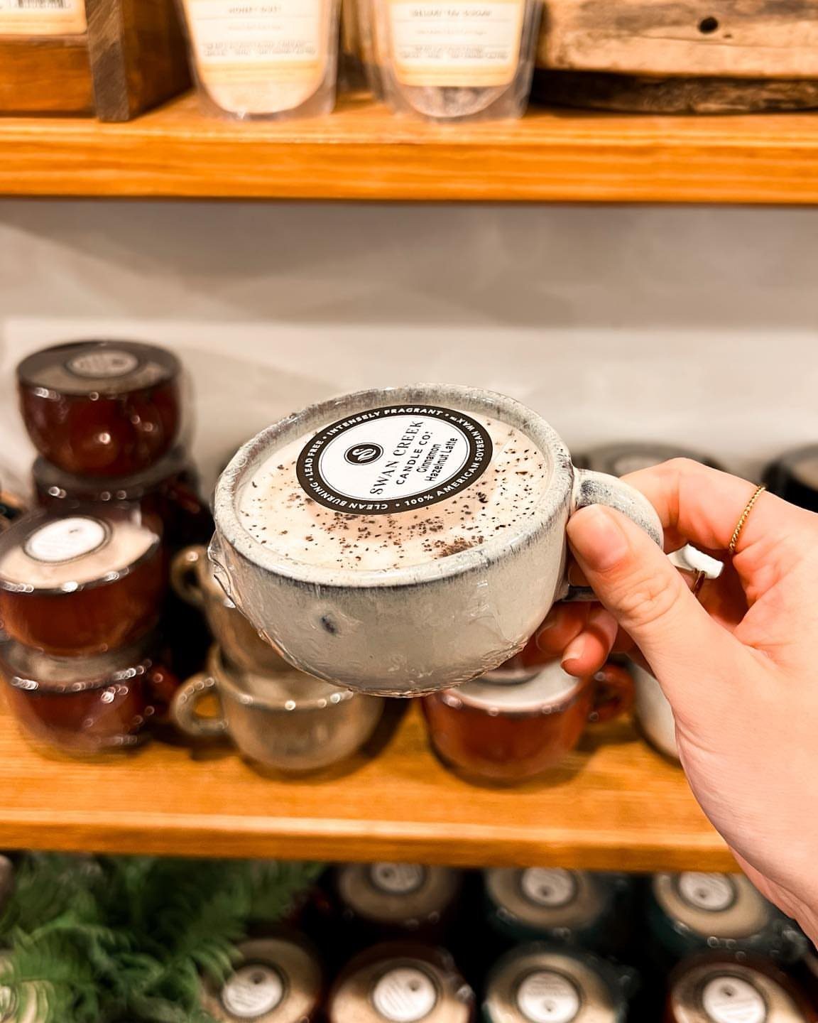 15 Coffee Drinker Gifts: Candles, Mugs, Roasters and More 8 Hand holding a candle shaped like a grey coffee mug with cream wax.