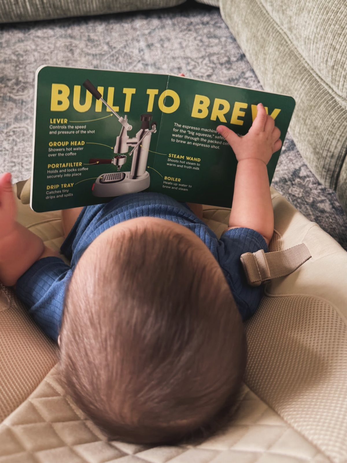 15 Coffee Drinker Gifts: Candles, Mugs, Roasters and More 13 Baby holding a green coffee-themed board book titled Built to Brew.