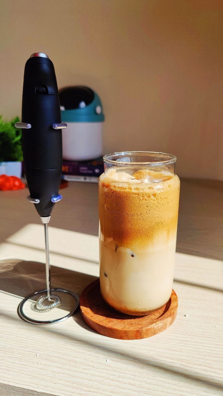 15 Coffee Drinker Gifts: Candles, Mugs, Roasters and More 4 Handheld milk frother standing next to a glass of iced coffee with foam.