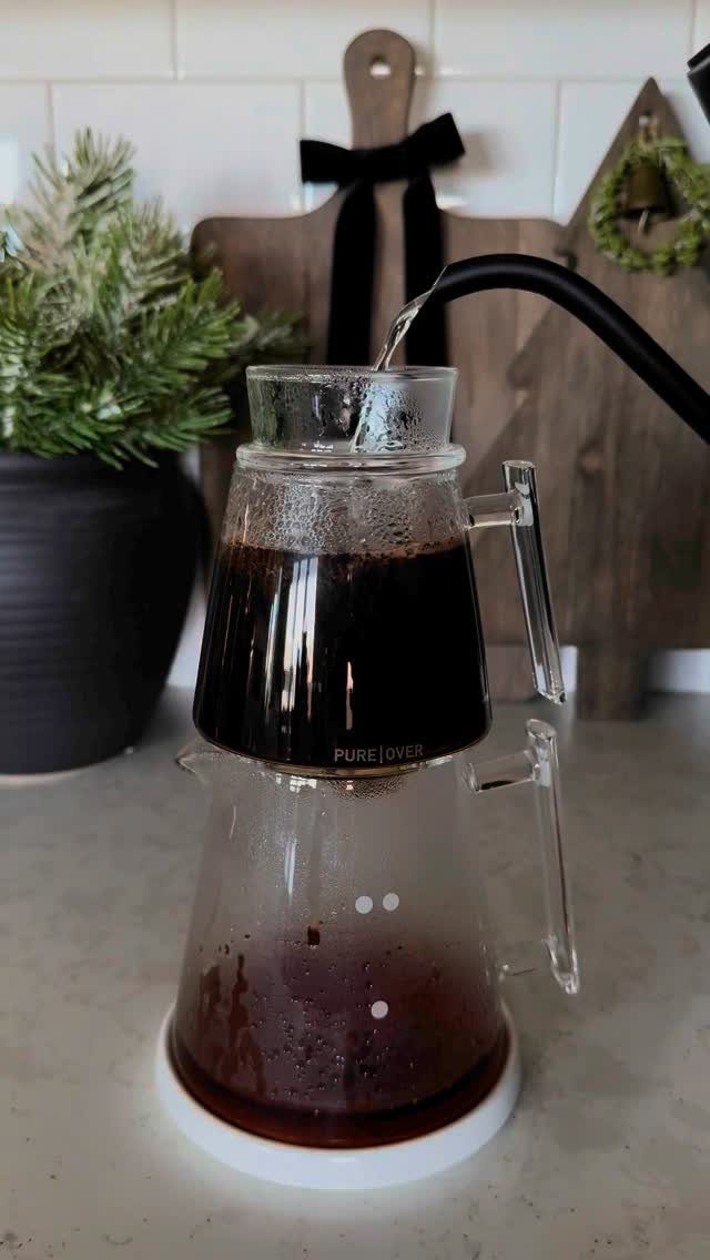 15 Coffee Drinker Gifts: Candles, Mugs, Roasters and More 3 Glass pour-over coffee maker brewing dark coffee with a black gooseneck kettle.