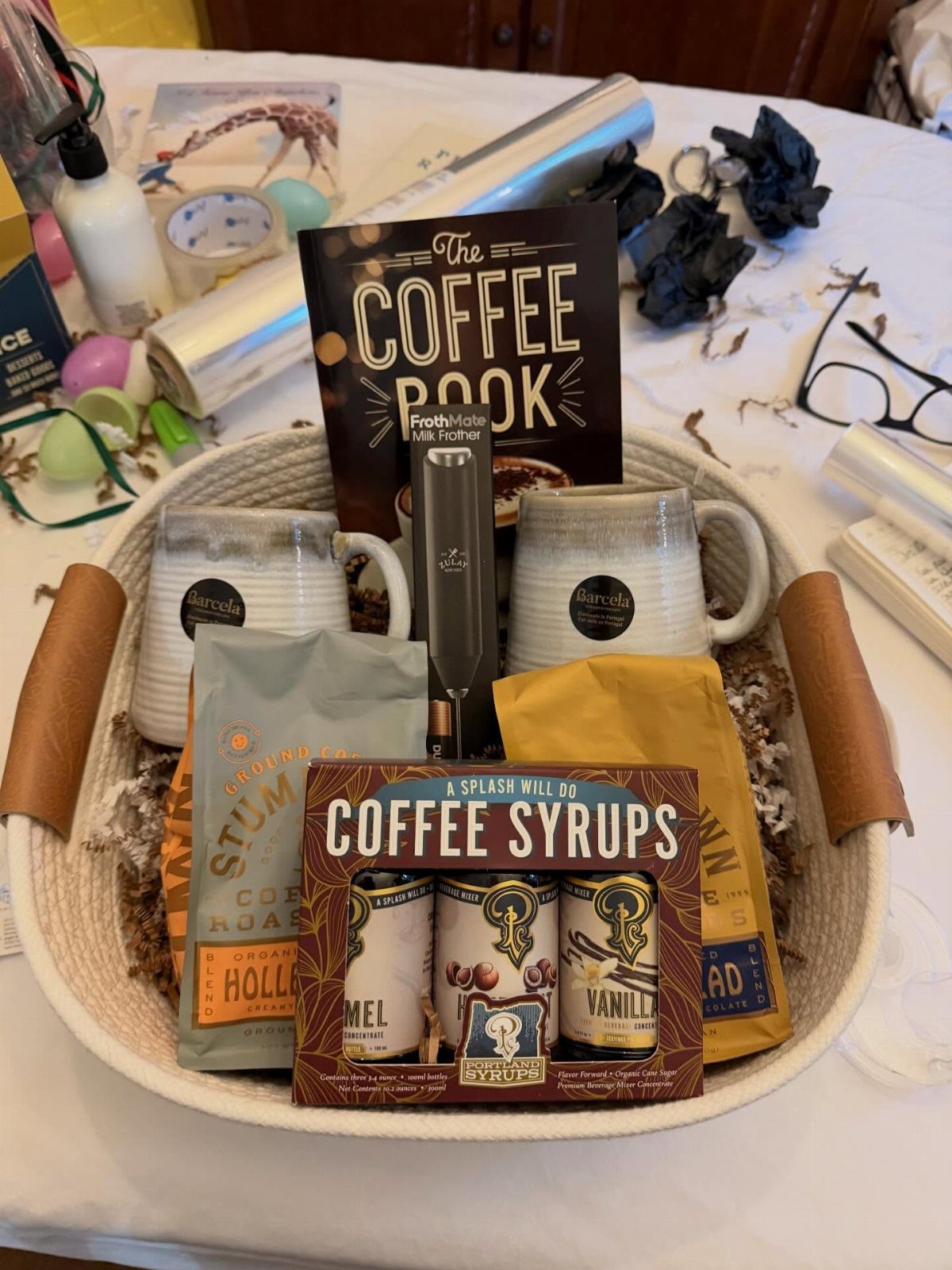 Coffee themed gift basket with mugs, coffee beans, syrups, and a coffee book.