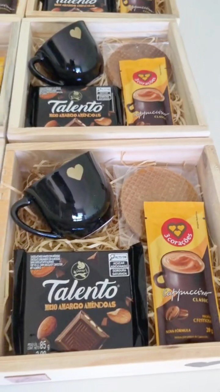 Coffee gift baskets in wooden crates with black mugs, chocolate, and cappuccino sachets.