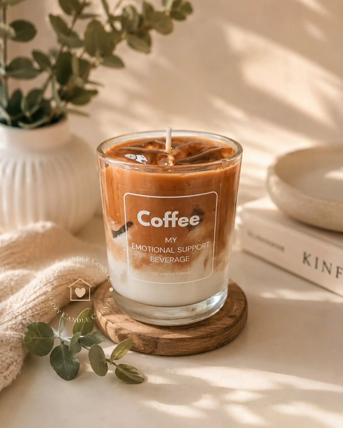 Coffee-scented candle designed to look like an iced latte on a wooden coaster