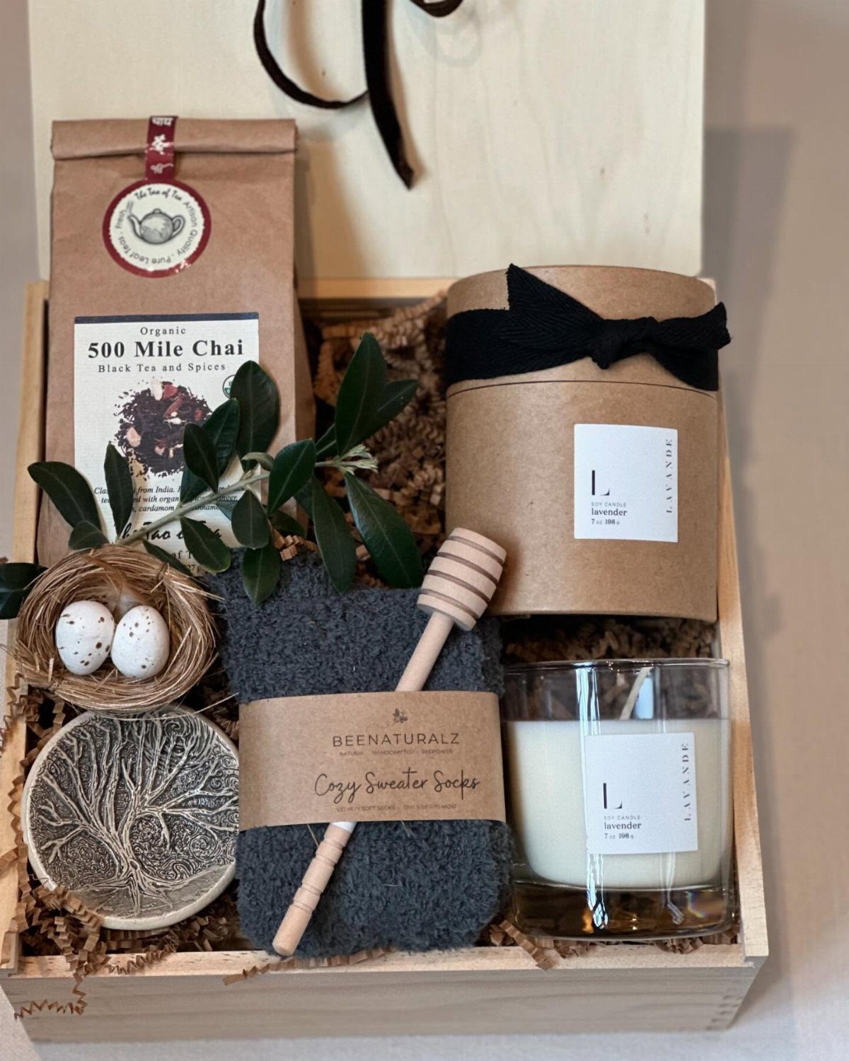 Comfort Gift Basket Ideas for Rough Days: 9 Picks 5 Wooden gift box with a scented candle, chai tea, cozy socks, and honey dipper.