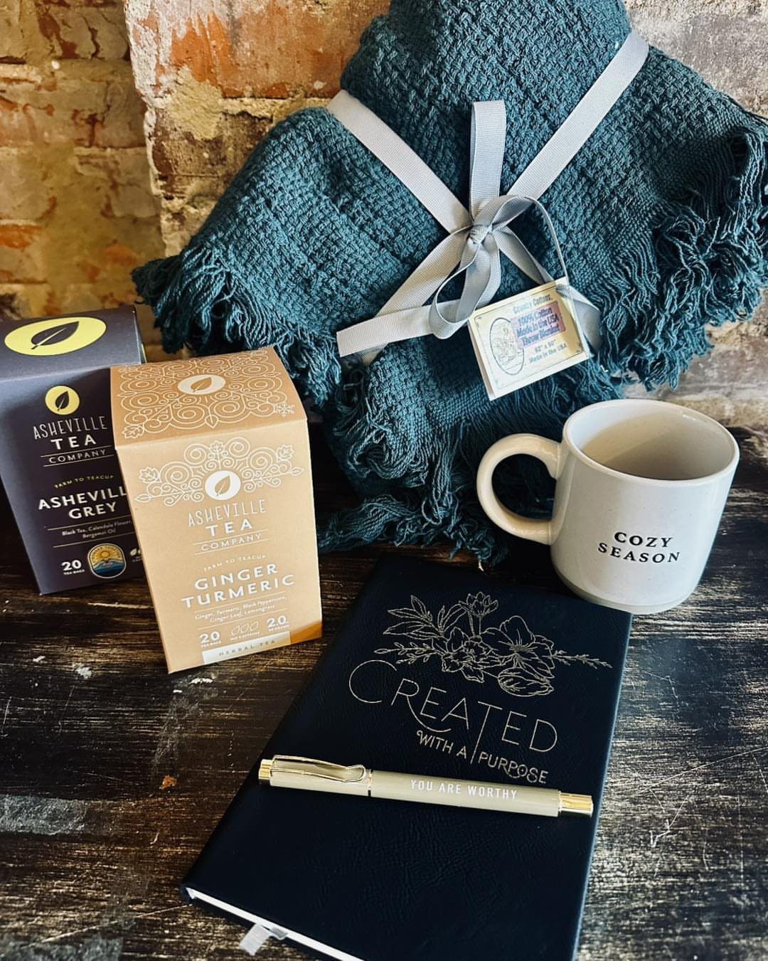 Comfort Gift Basket Ideas for Rough Days: 9 Picks 3 Teal blanket, tea boxes, a cozy season mug, and a notebook on wood.