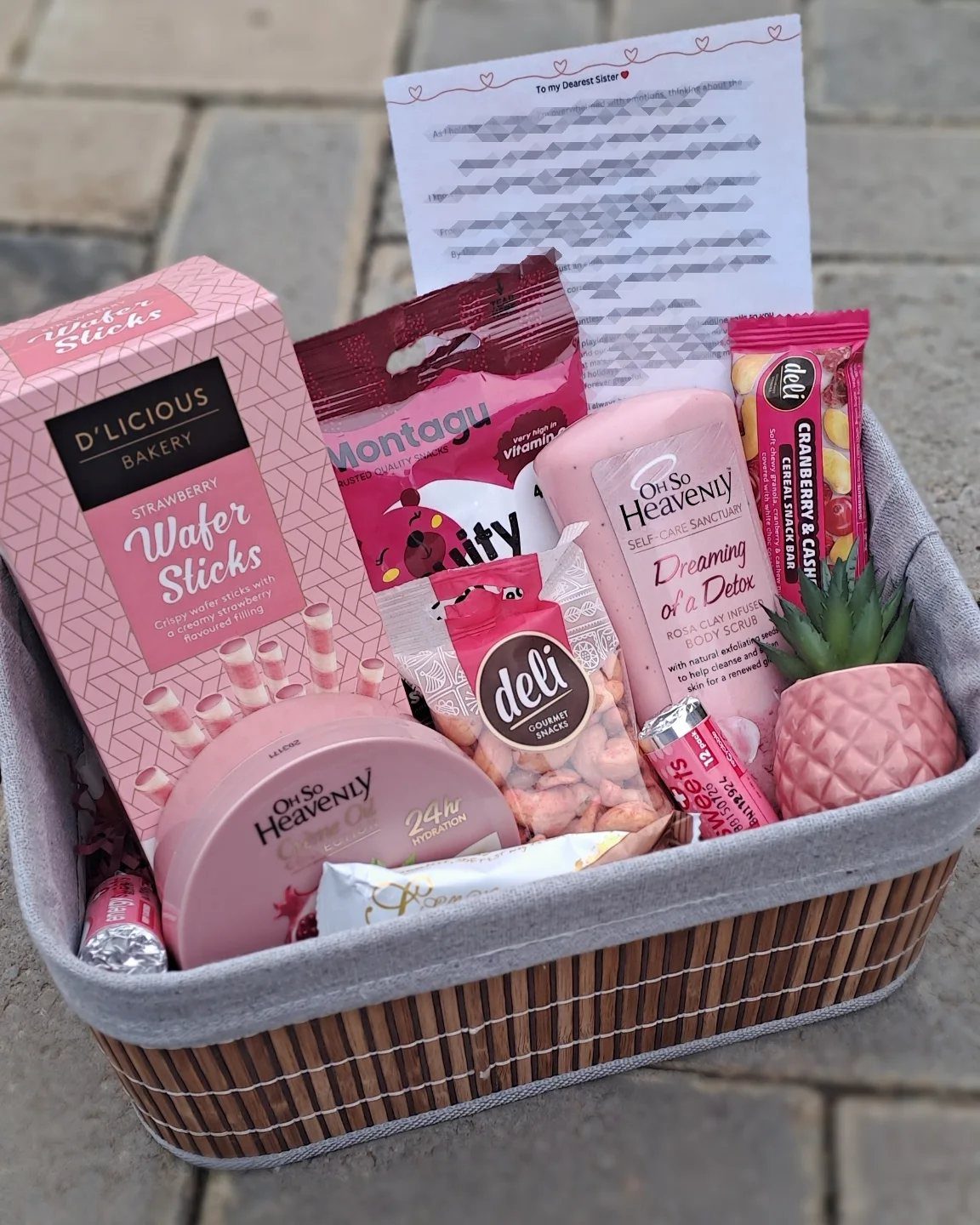 Comfort Gift Basket Ideas for Rough Days: 9 Picks 6 Woven gift basket filled with pink snacks, a candle, and a handwritten note.