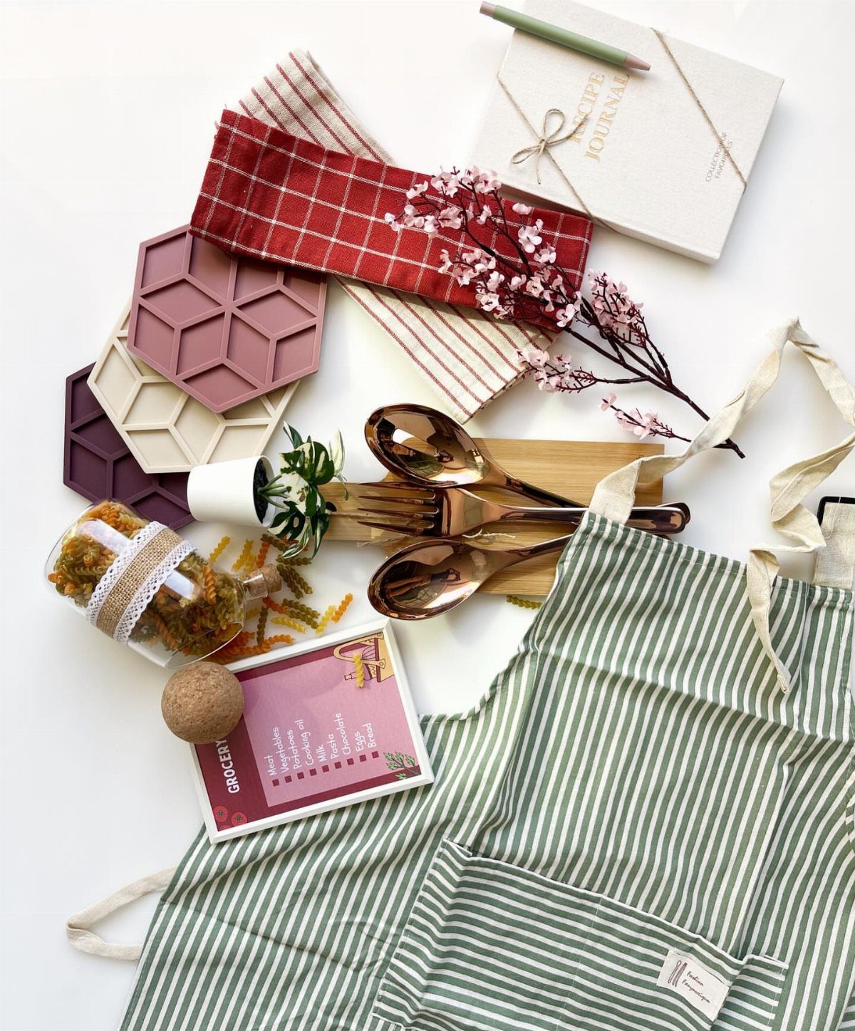 Cooking gift set with a green striped apron, gold utensils, and recipe journal.