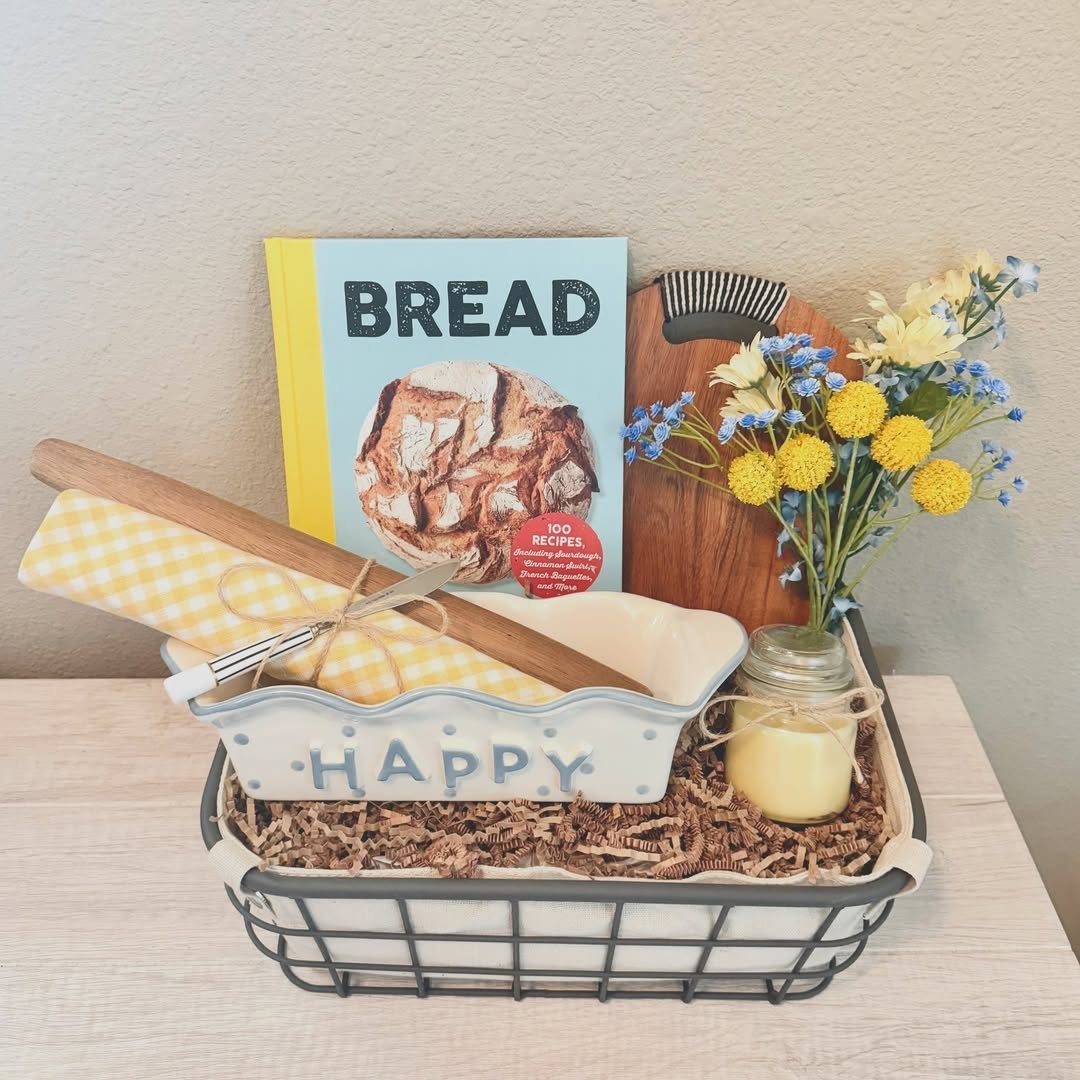 Baking gift basket with bread cookbook, rolling pin, ceramic dish, and yellow flowers.