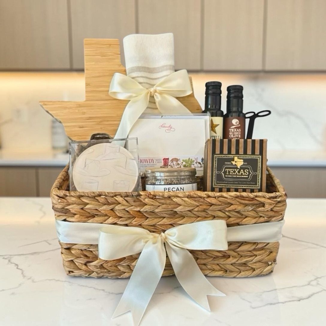 Woven gift basket with Texas-shaped cutting board, pecan nuts, and Texas-themed condiments.