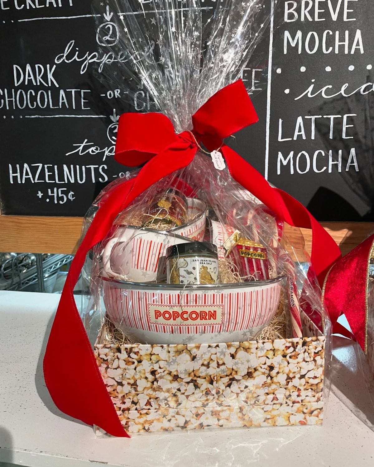 Popcorn themed gift basket wrapped in cellophane with a large red bow.