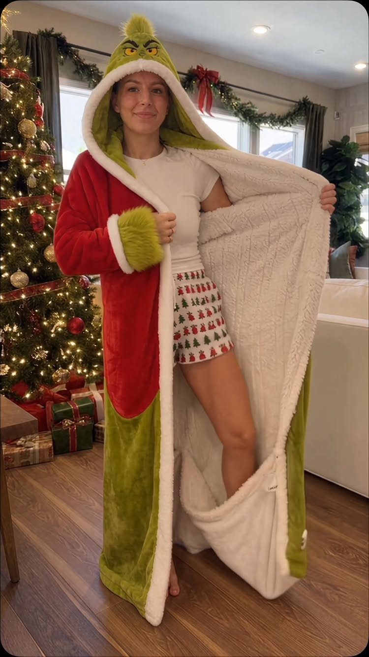 21 Cool Gifts for Adults: Practical Picks for 2026 14 Woman wearing a red and green Grinch wearable blanket beside a Christmas tree.