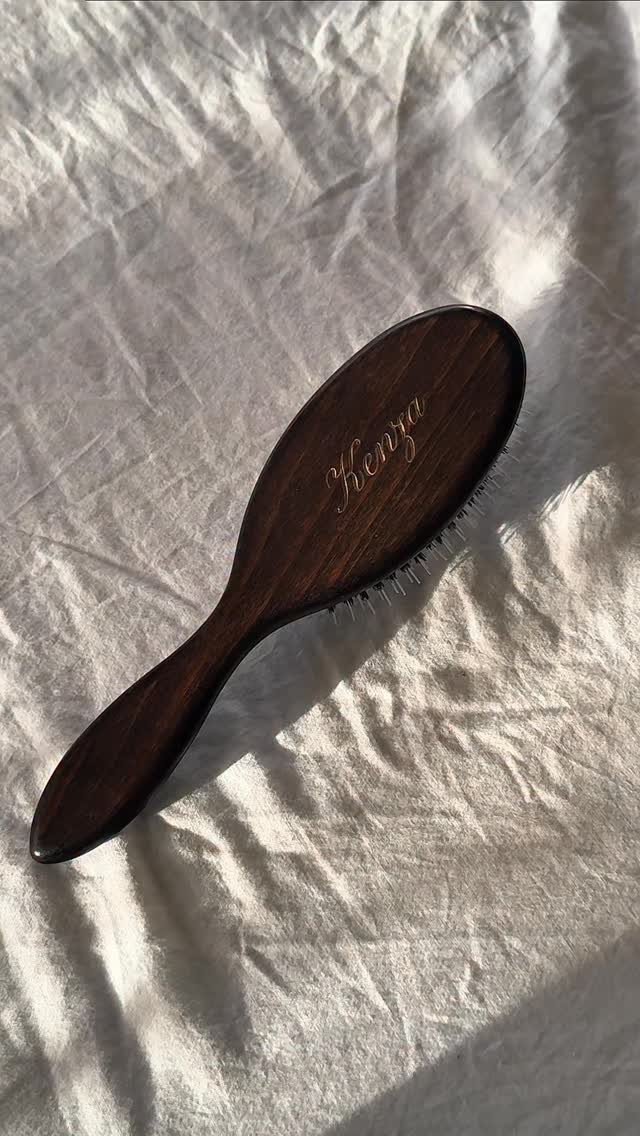 21 Cool Gifts for Adults: Practical Picks for 2026 4 Dark brown wooden hairbrush with gold lettering resting on white wrinkled fabric.